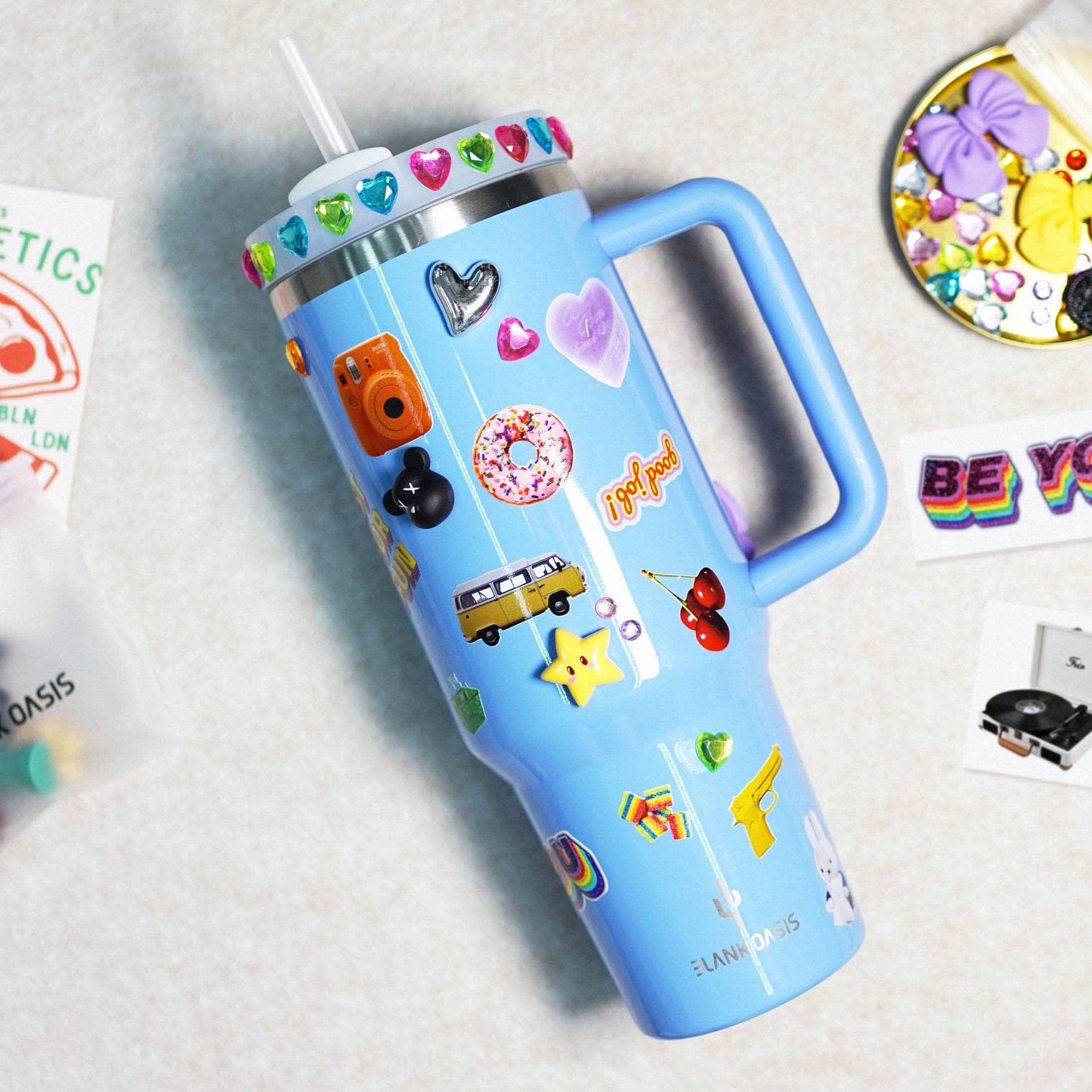 A blue 40OZ tumbler with stickers and flatback charms